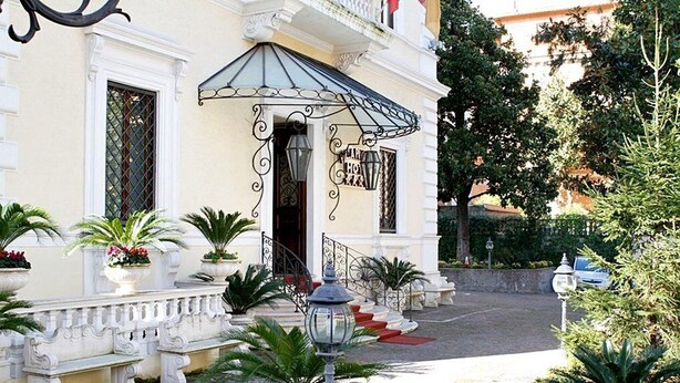 A building with a white facade, a covered entrance, and a staircase leading to the entrance. - Villa Pinciana (Rome)