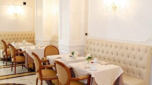A formal dining room with multiple tables, chairs, and a tufted sofa. - Villa Pinciana (Rome)