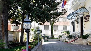 A cobblestone pathway leading to a building with a staircase and a flag. - Villa Pinciana (Rome)