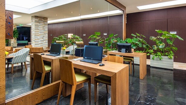 Un espace de bureau moderne doté de bureaux en bois, de chaises ergonomiques et de plusieurs ordinateurs portables.