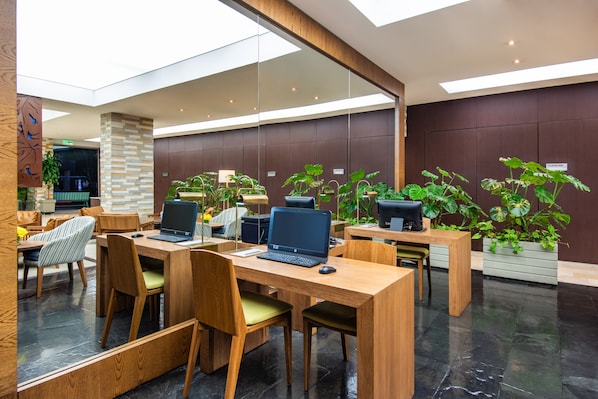 A modern office space with wooden desks, ergonomic chairs, and multiple laptops.