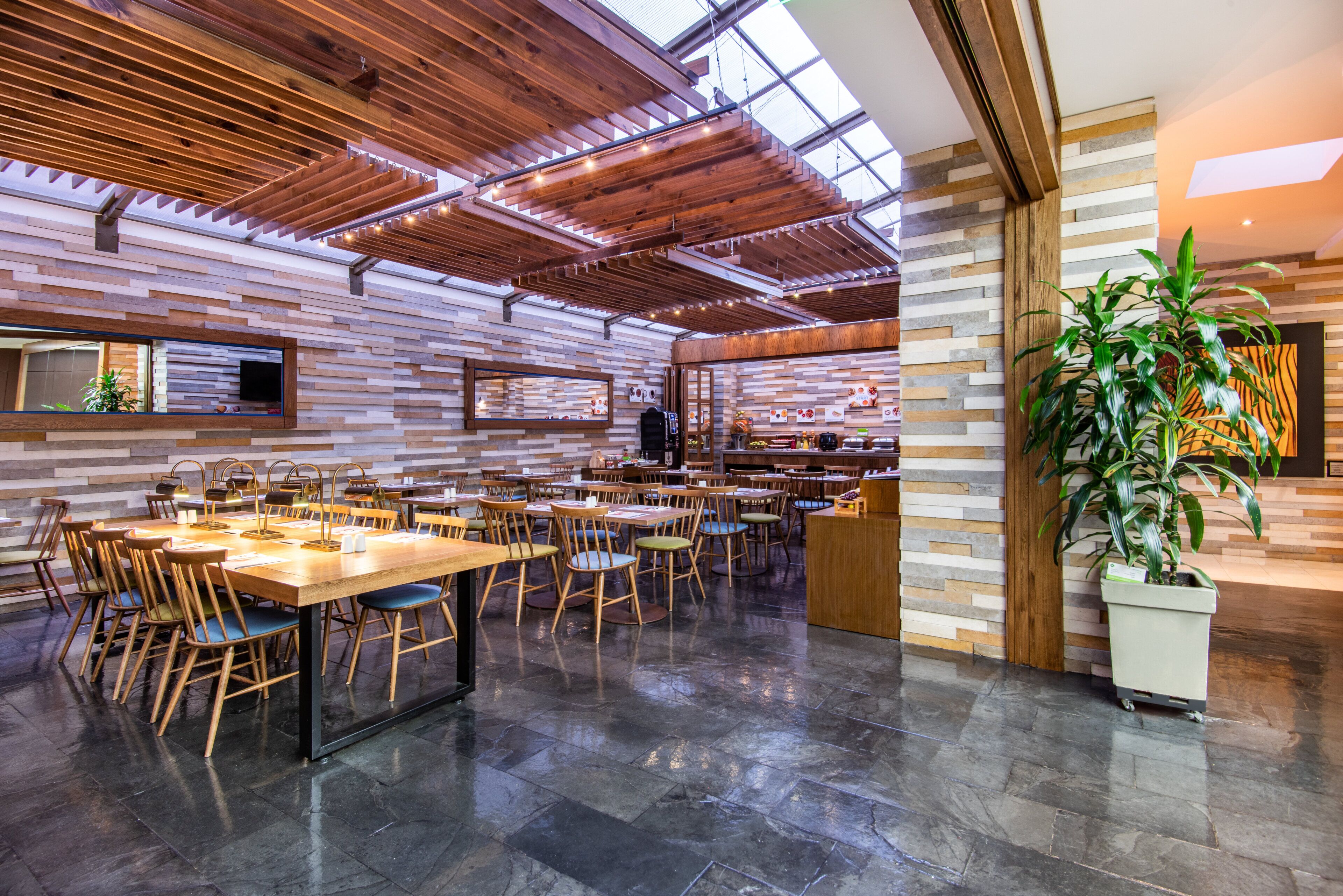 A spacious restaurant with high ceilings, wooden beams, and a variety of seating arrangements.