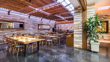 Un restaurante amplio con techos altos, vigas de madera y diversas opciones de asientos.