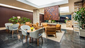 A spacious lobby with a seating area featuring striped chairs and sofas, a central coffee table, and a decorative wall with leaf patterns. - Holiday Inn Express Bogotá - Parque La 93 by IHG (Bogotá)