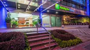 A Holiday Inn Express building with a modern facade, outdoor seating area, and a staircase leading to the entrance. - Holiday Inn Express Bogotá - Parque La 93 by IHG (Bogotá)