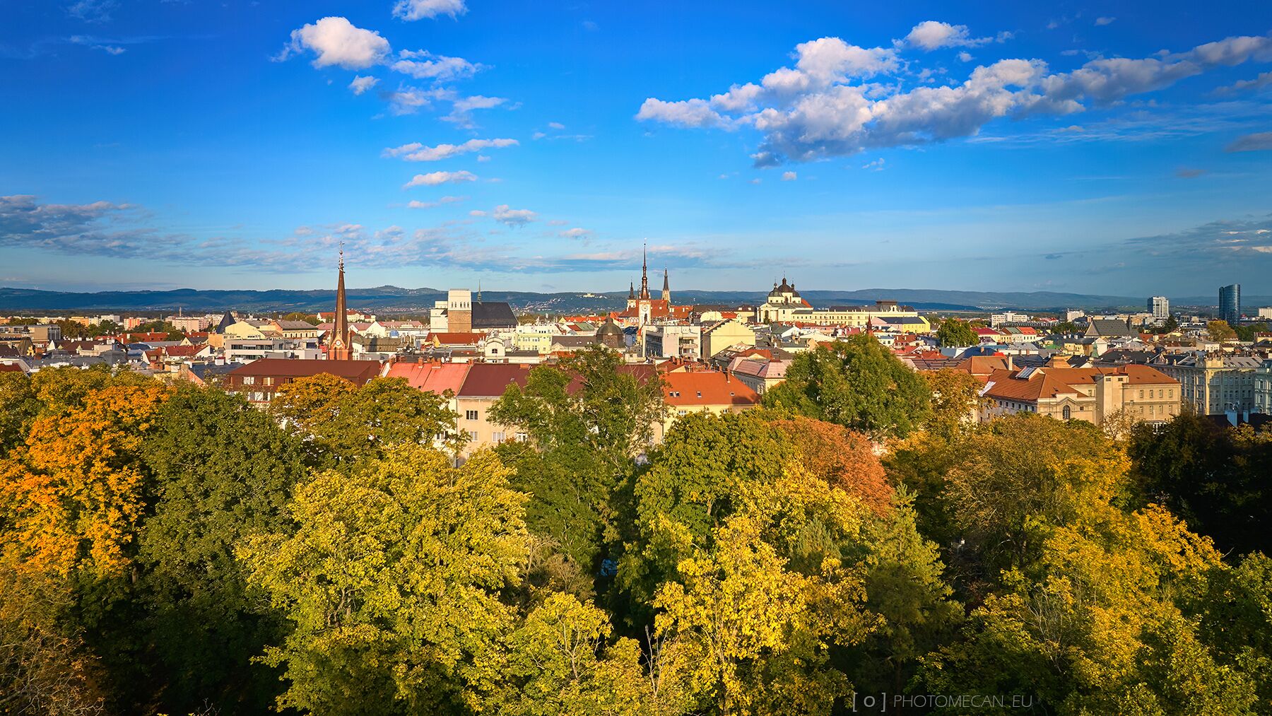 A panoramic view of a city with historic buildings, a prominent church, and a mix of residential and commercial structures.