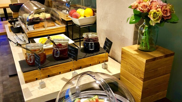 A buffet with various food items, including a watermelon display and a bowl of grapes. - Central Park Flora (Olomouc)