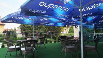 Outdoor seating with wicker chairs and tables under blue umbrellas with 'DUPONOD' branding.