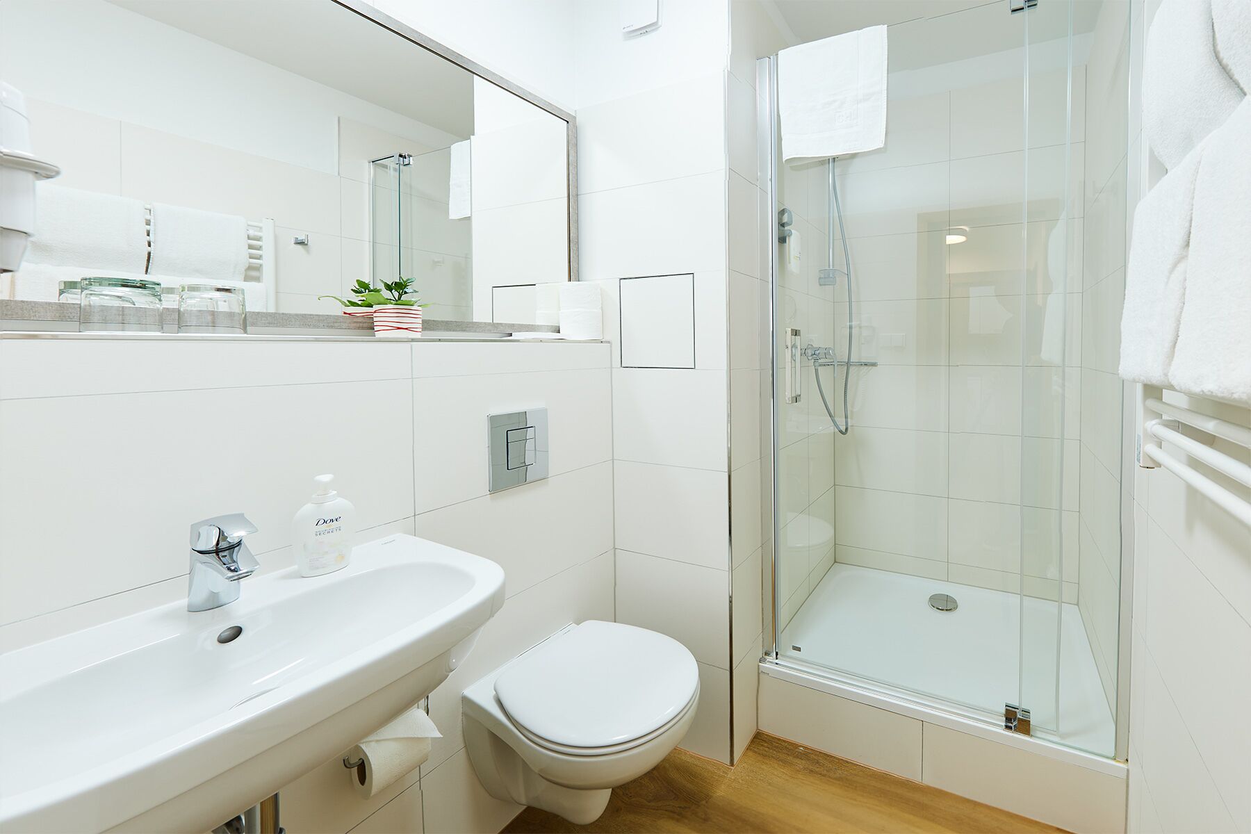 Une salle de bain moderne avec une douche à parois de verre, un lavabo blanc et des toilettes.