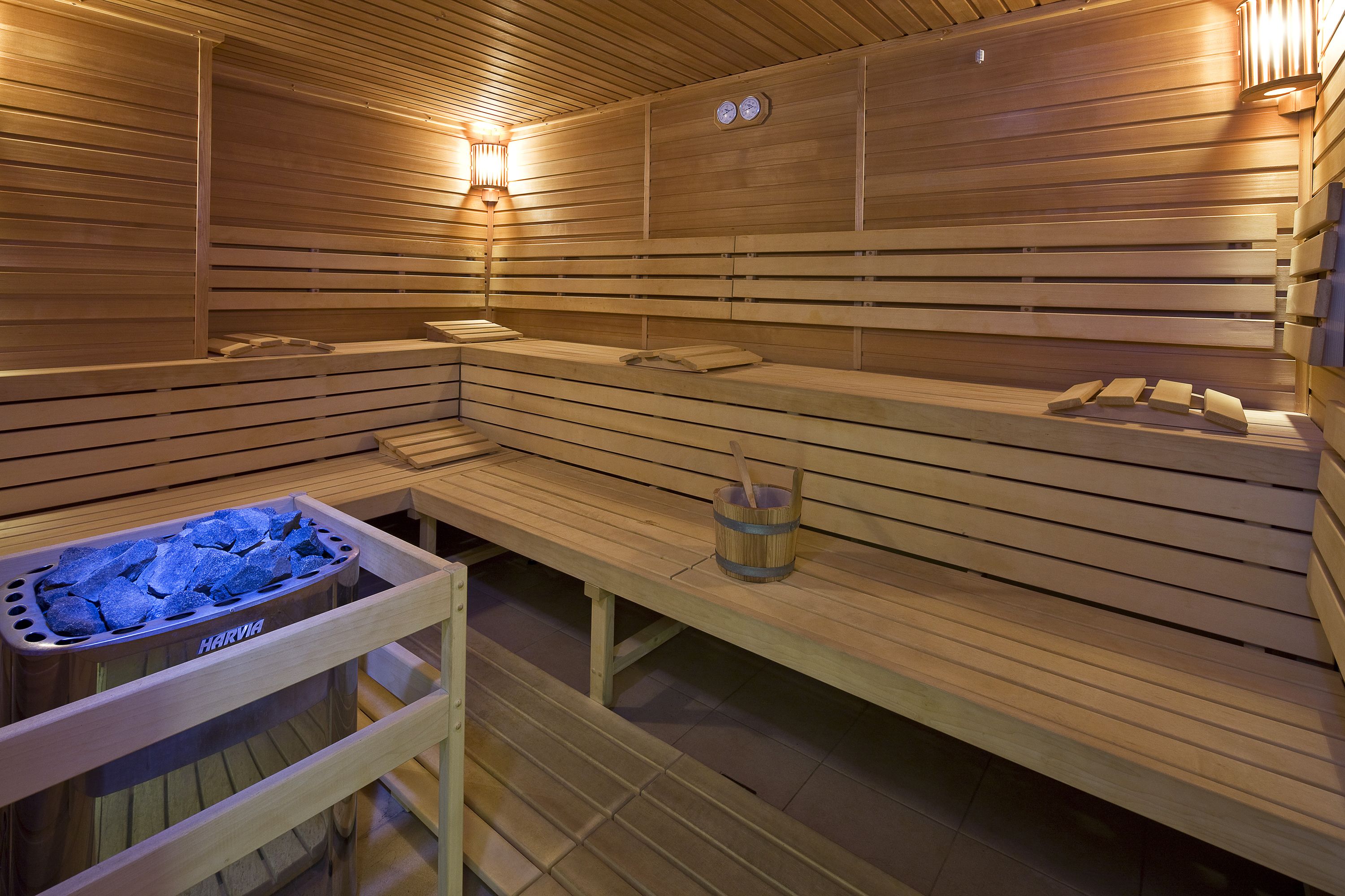 A sauna with wooden benches, a bench heater, and a stone basin.