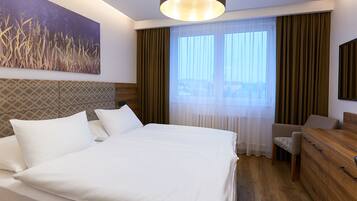 A hotel room with a large bed, a wooden headboard, a desk, and a chair. There is a painting on the wall and a window with curtains.