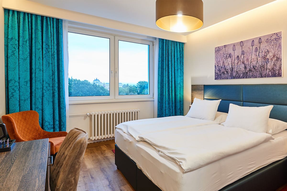 Een hotelkamer met een groot bed, een bureau, een stoel en uitzicht op de stad.