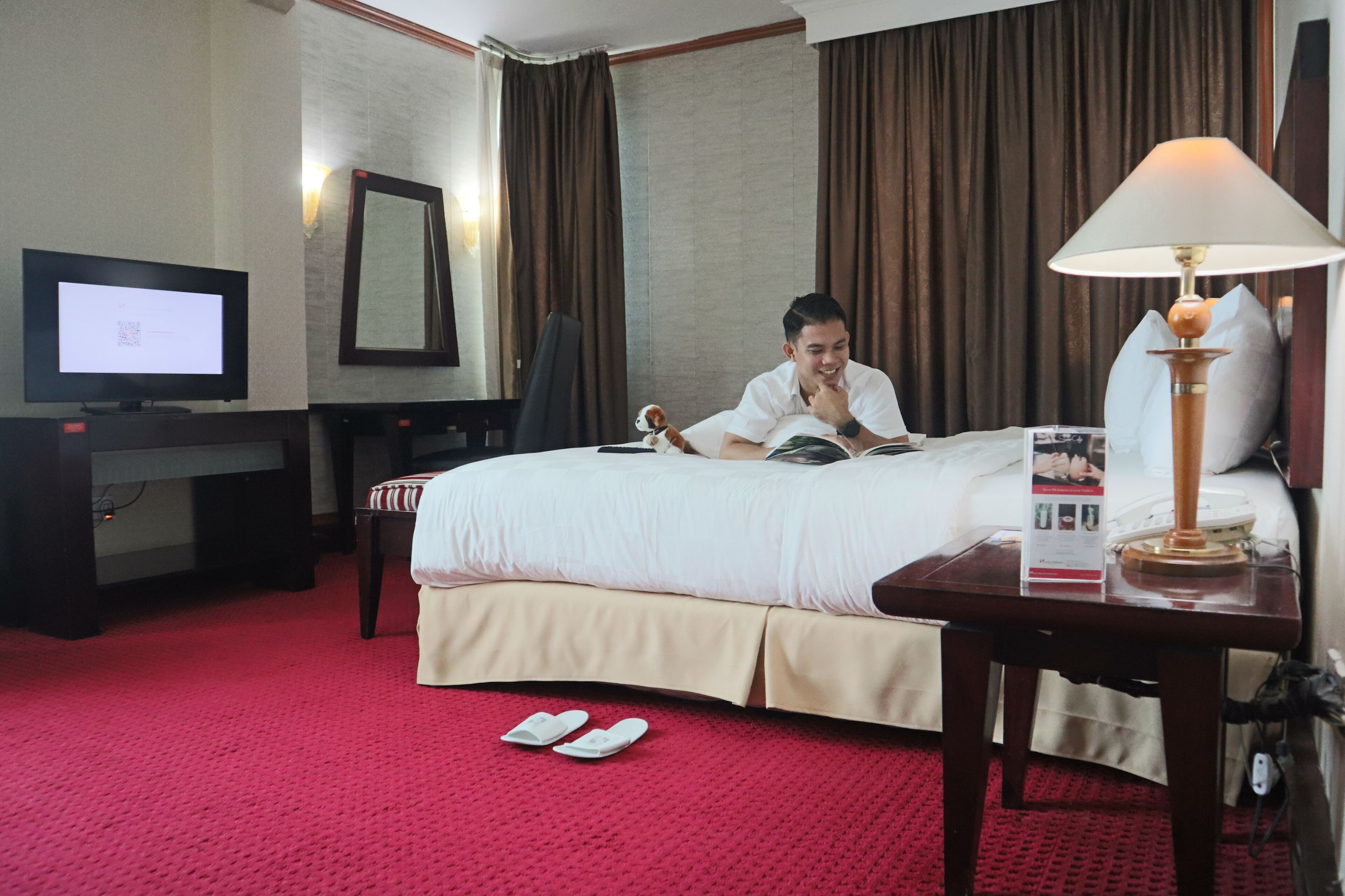A hotel room with a bed, a desk, a television, and a lamp.