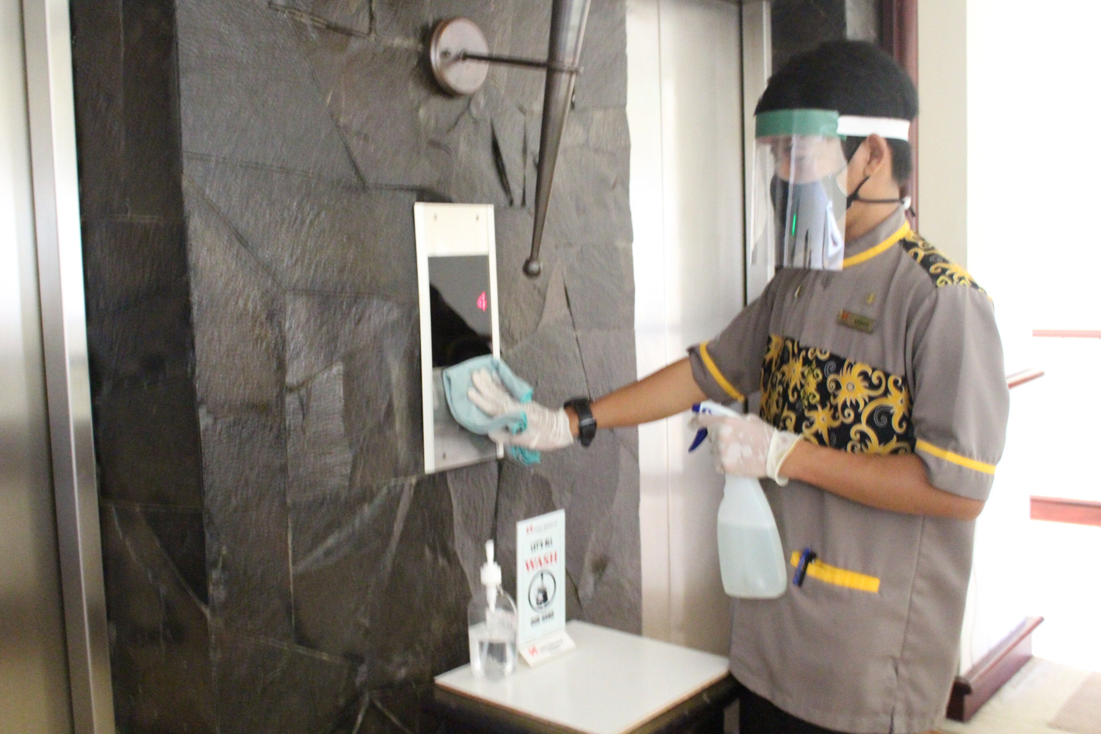 A person cleaning a wall with a spray bottle and a cloth.