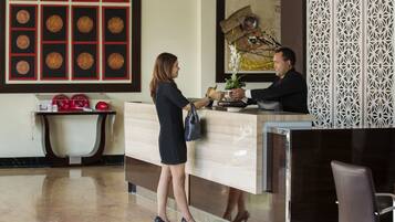 A reception area with a modern design, featuring a reception desk, a decorative wall with circular patterns, and a potted plant.