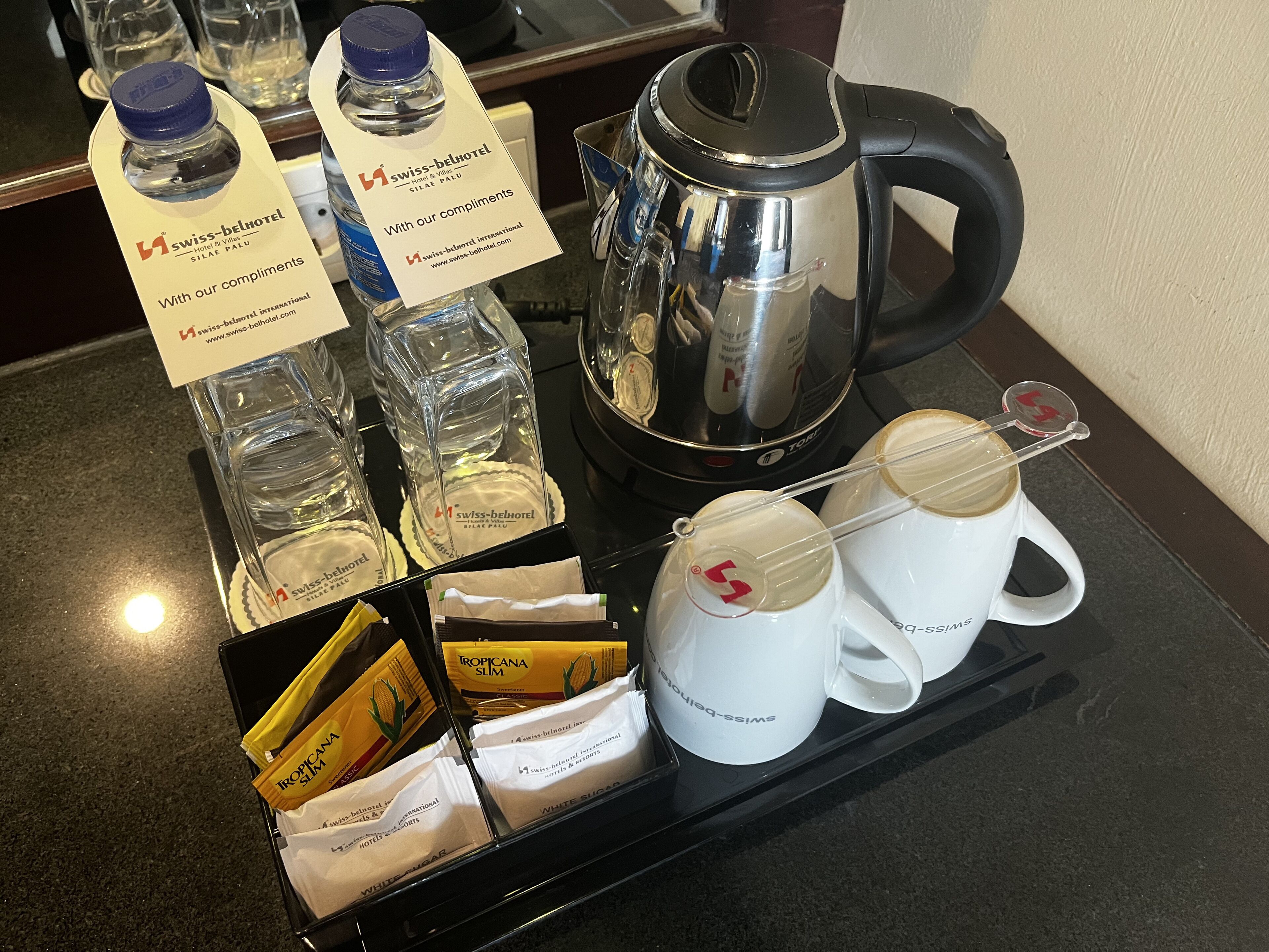 Ein Frühstückswagen mit Wasserflaschen, einer Kaffeekanne, einem Teekessel und verpackten Lebensmitteln.