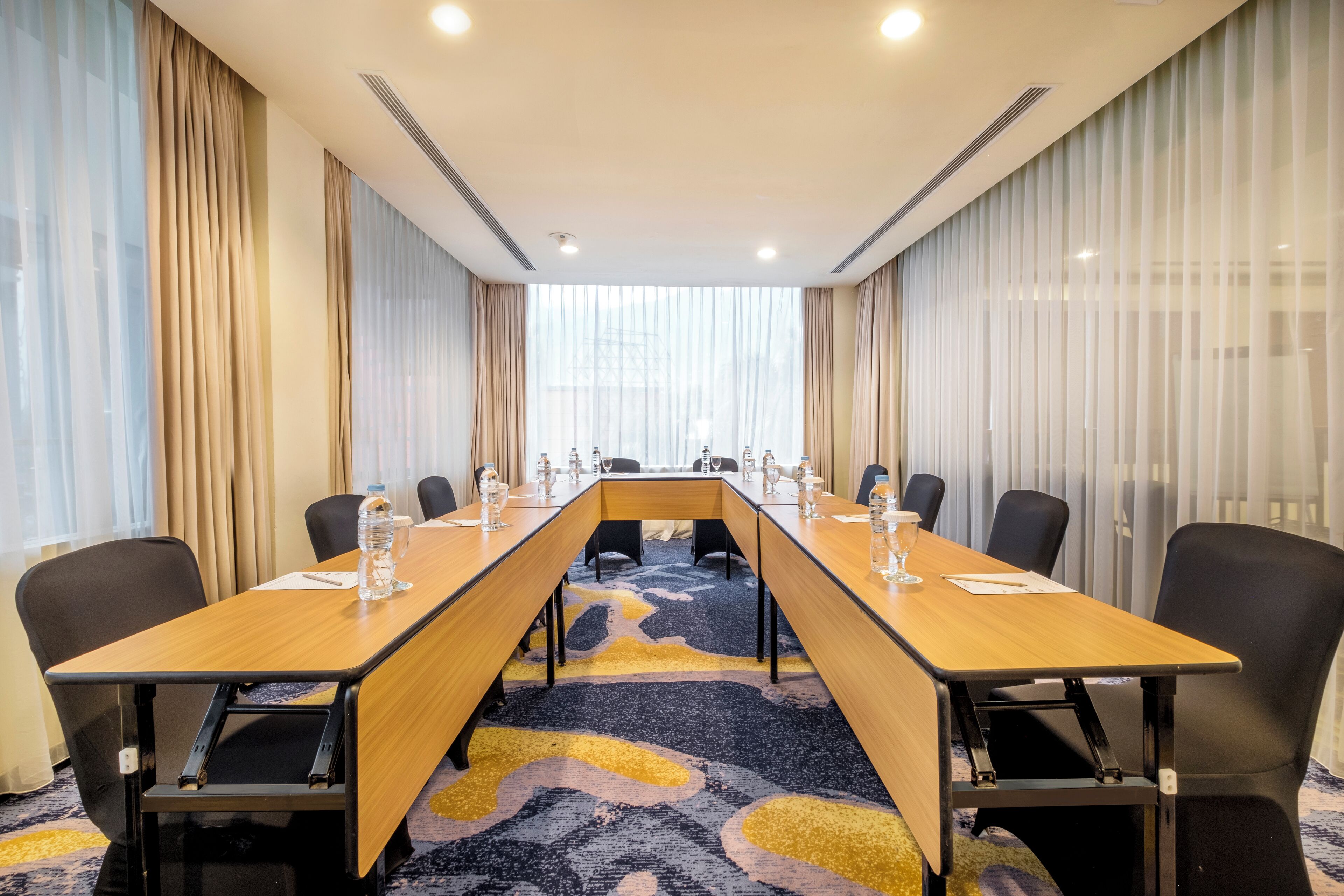 A conference room with a long table, chairs, and a carpeted floor.