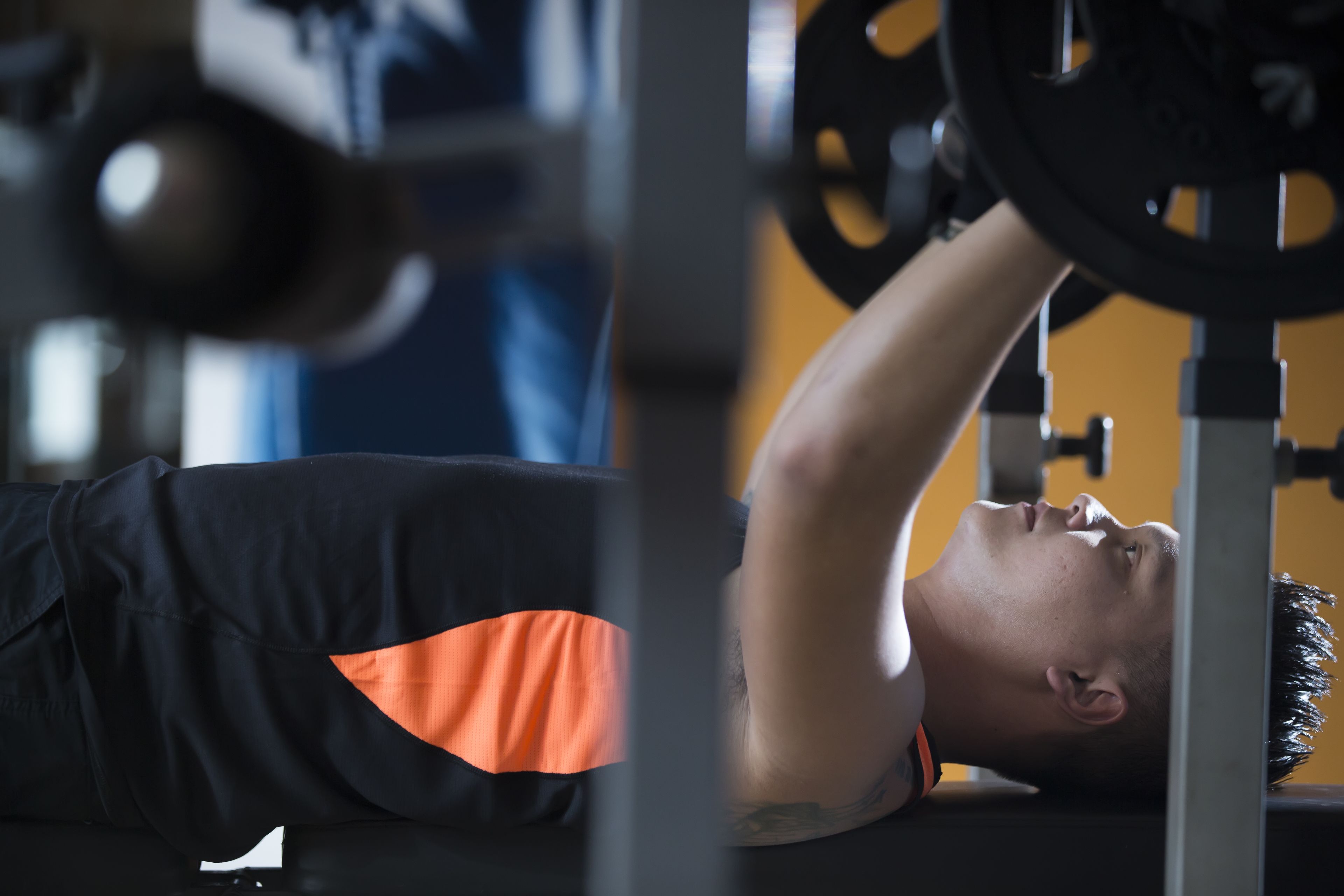 A person lying on a bench, performing a bench press exercise with a barbell.