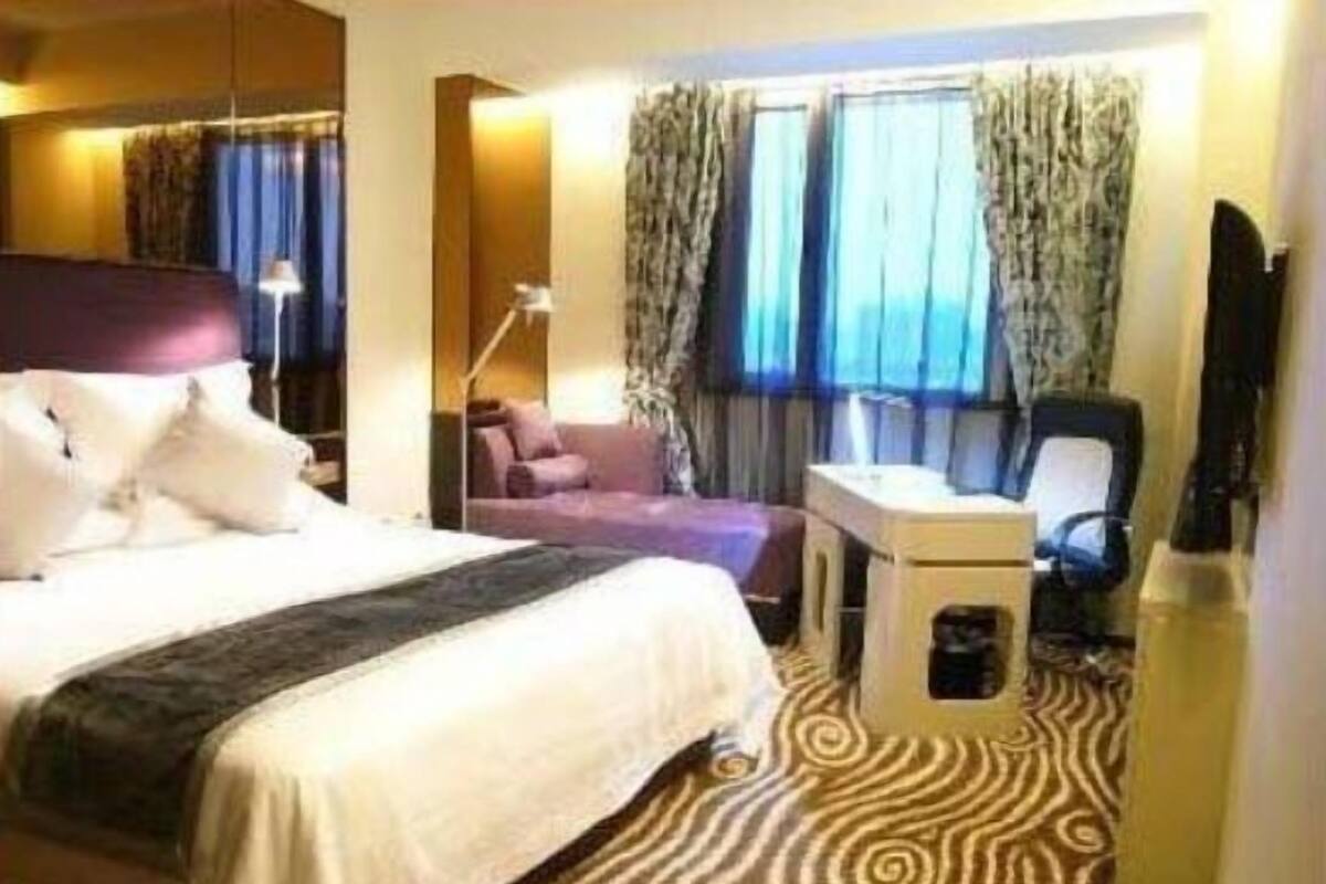 A hotel room with a large bed, a desk, a chair, and a television.