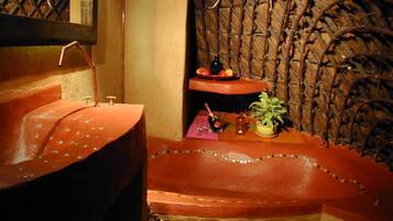 Bathroom features a curved sink, mirror, and a shelf with a potted plant.