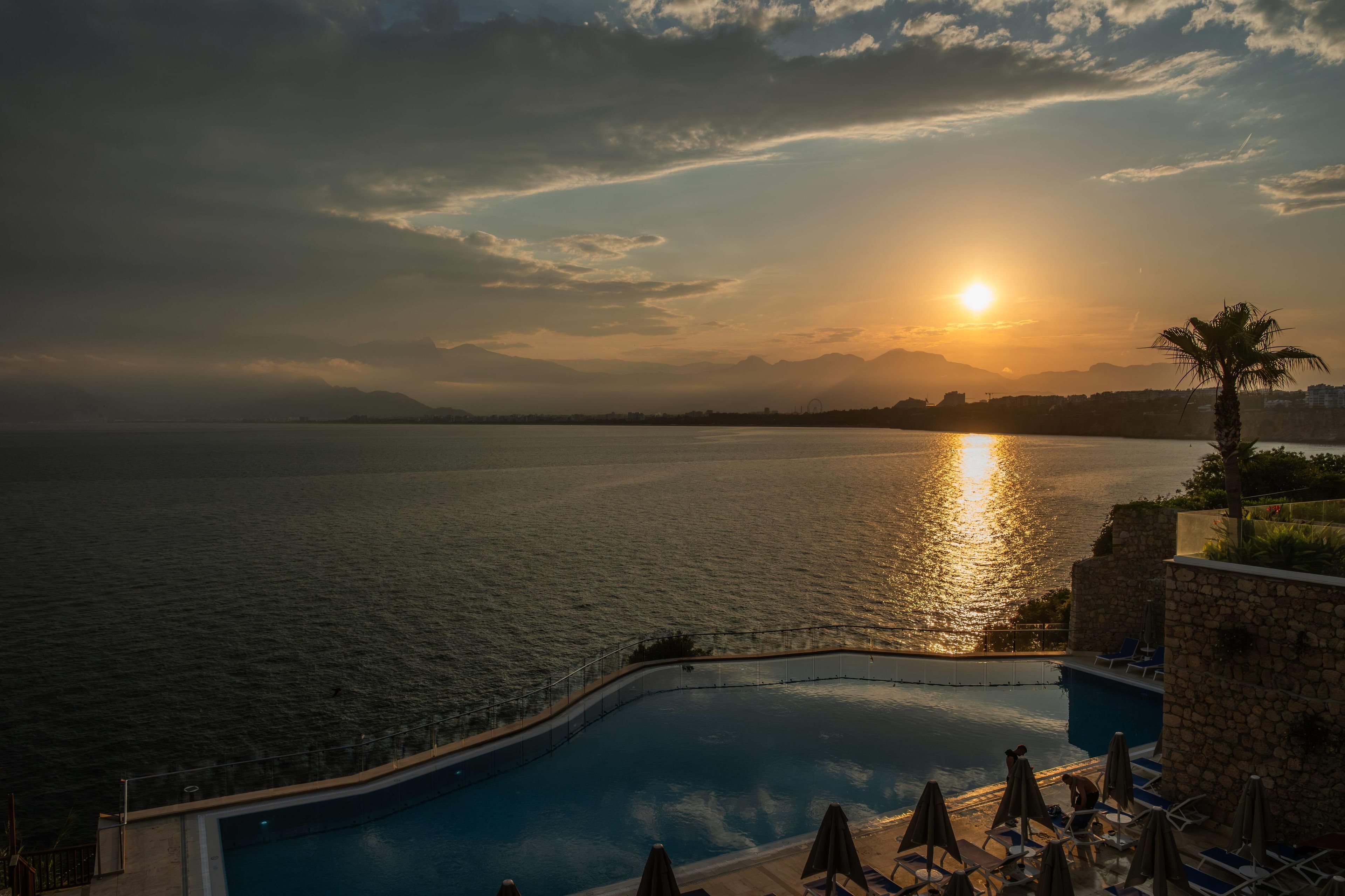 Una piscina con vistas al mar y a las montañas durante el atardecer.