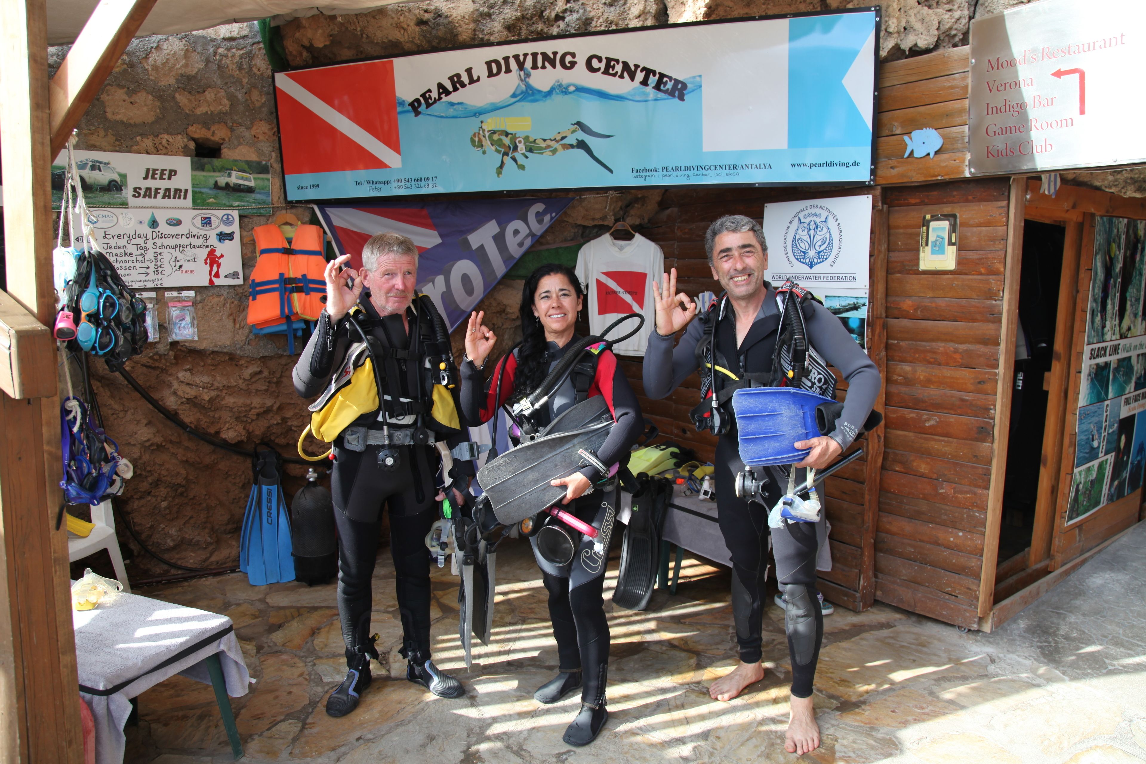 A diving center with a sign for 'Pearl Diving Center' and a 'Jeep Safari' sign. There are diving suits and equipment visible.