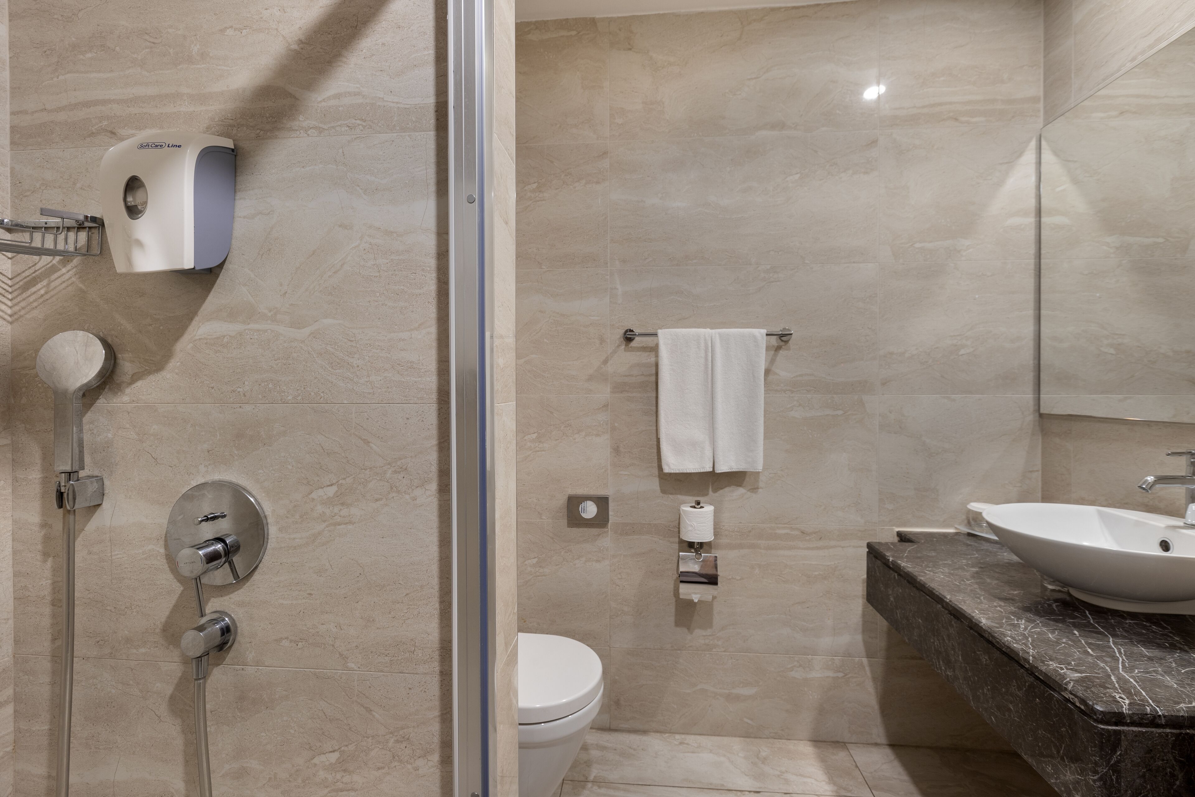 A modern bathroom with a glass-enclosed shower, a toilet, a sink with a marble countertop, and a towel rack.