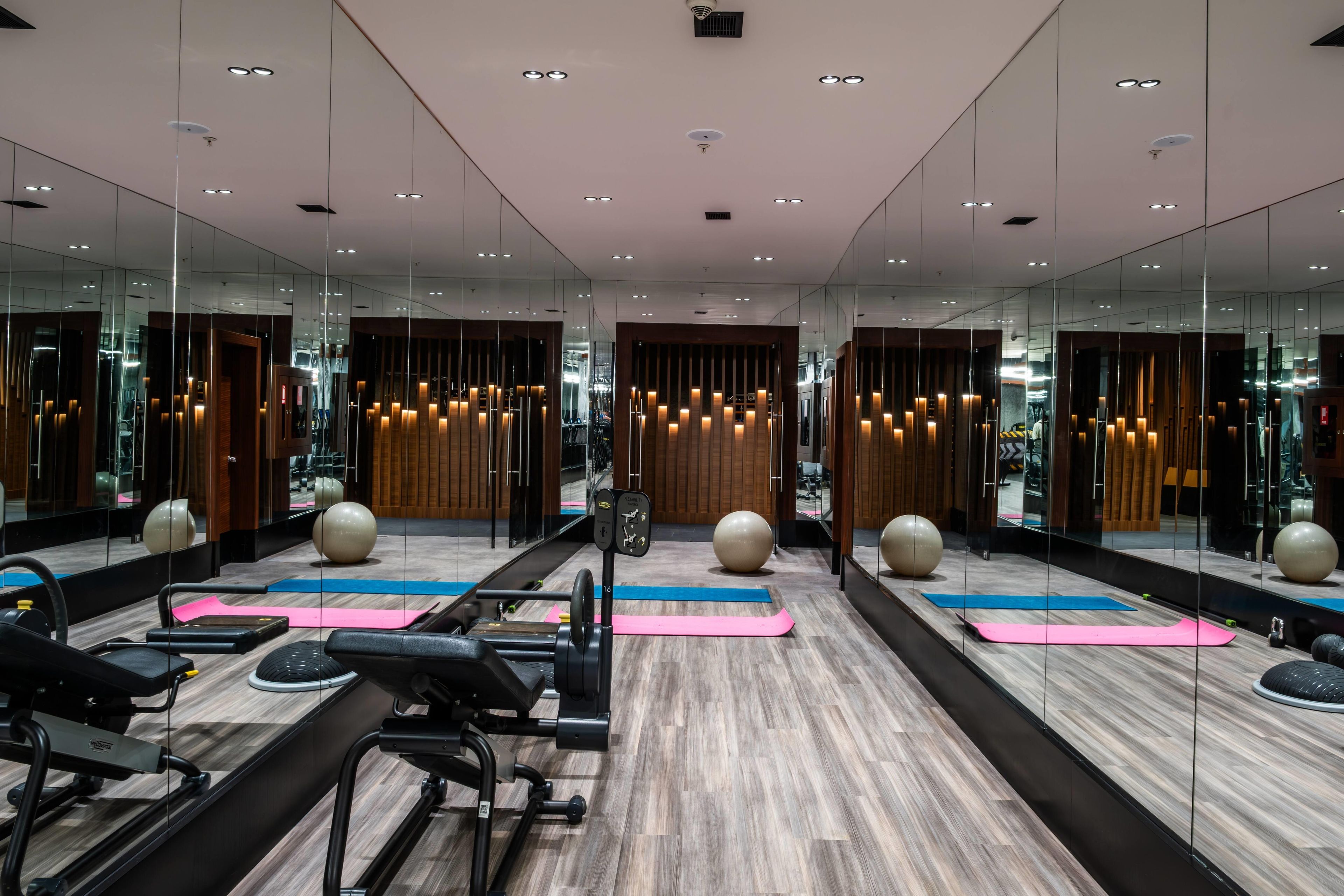 Een sportschool met trainingsapparatuur, spiegelwanden en houten details.