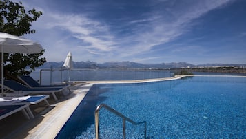Relax by the pool surrounded by lounge chairs and umbrellas, with a view of the distant mountains.