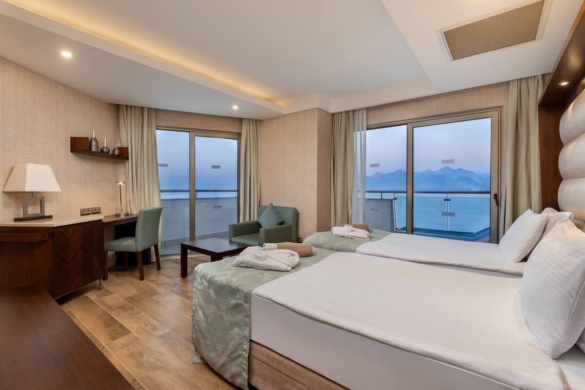 Une chambre d’hôtel avec deux lits, un bureau, une chaise et une vue sur la mer.