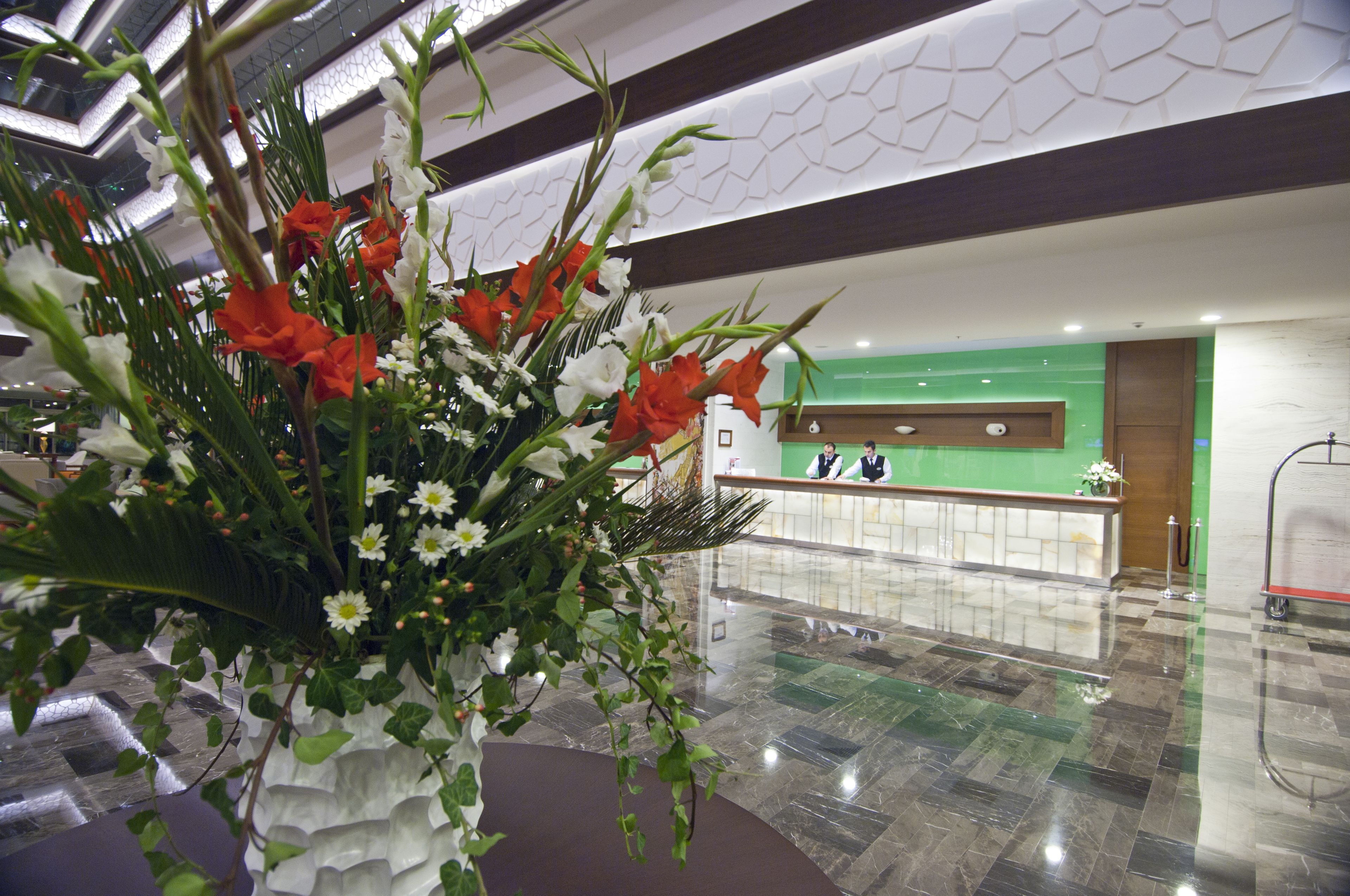 A reception area with a green wall, a reception desk, and a large floral arrangement.
