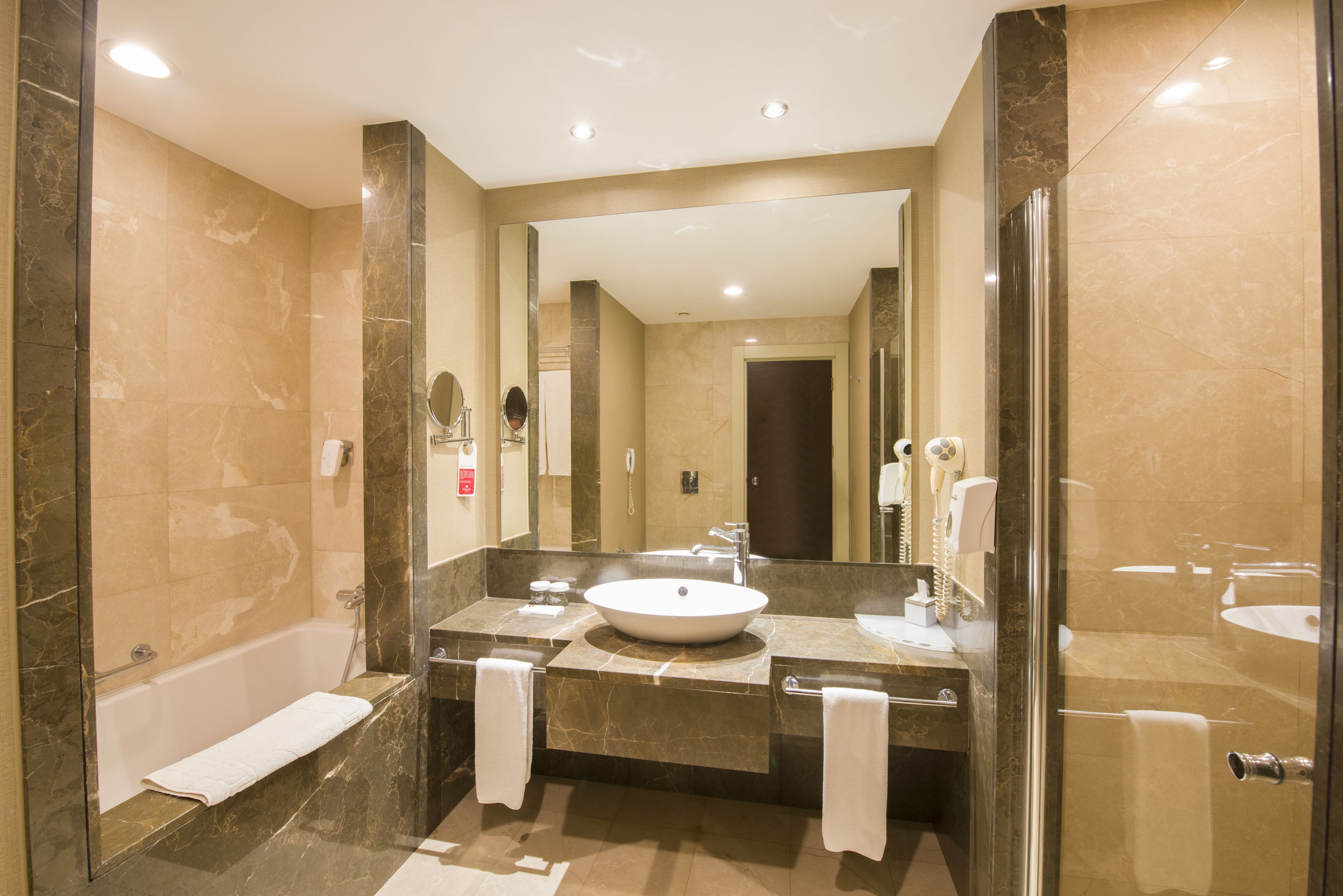 Une salle de bain moderne avec un grand miroir, une baignoire et un lavabo.