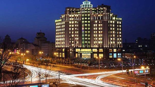 A multi-story hotel with a central dome and numerous windows, surrounded by a busy intersection with light trails from moving vehicles. - New Century Grand Hotel Changchun (Changchun)