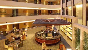 A multi-level hotel lobby with a glass ceiling, a central seating area, and a staircase. - New Century Grand Hotel Changchun (Changchun)