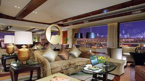 A spacious living room with a sofa, armchairs, and a coffee table. A large window offers a city view. - New Century Grand Hotel Changchun (Changchun)