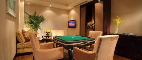 Una sala de billar con mesa de pool, sillas con reposabrazos, un sofá y una televisión.