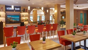 A modern lobby with a bar area, wooden tables, and orange chairs. - Diamond Hotel (Sunny Beach)