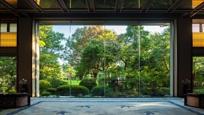 A traditional Japanese interior with tatami flooring, a shoji screen door, and a view of a lush garden. - Tokiwa Hotel (Kofu)