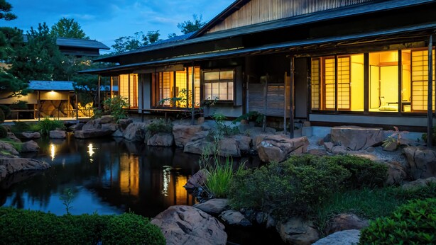 A traditional Japanese-style house with a koi pond in the foreground, large windows, and a well-maintained garden. - Tokiwa Hotel (Kofu)