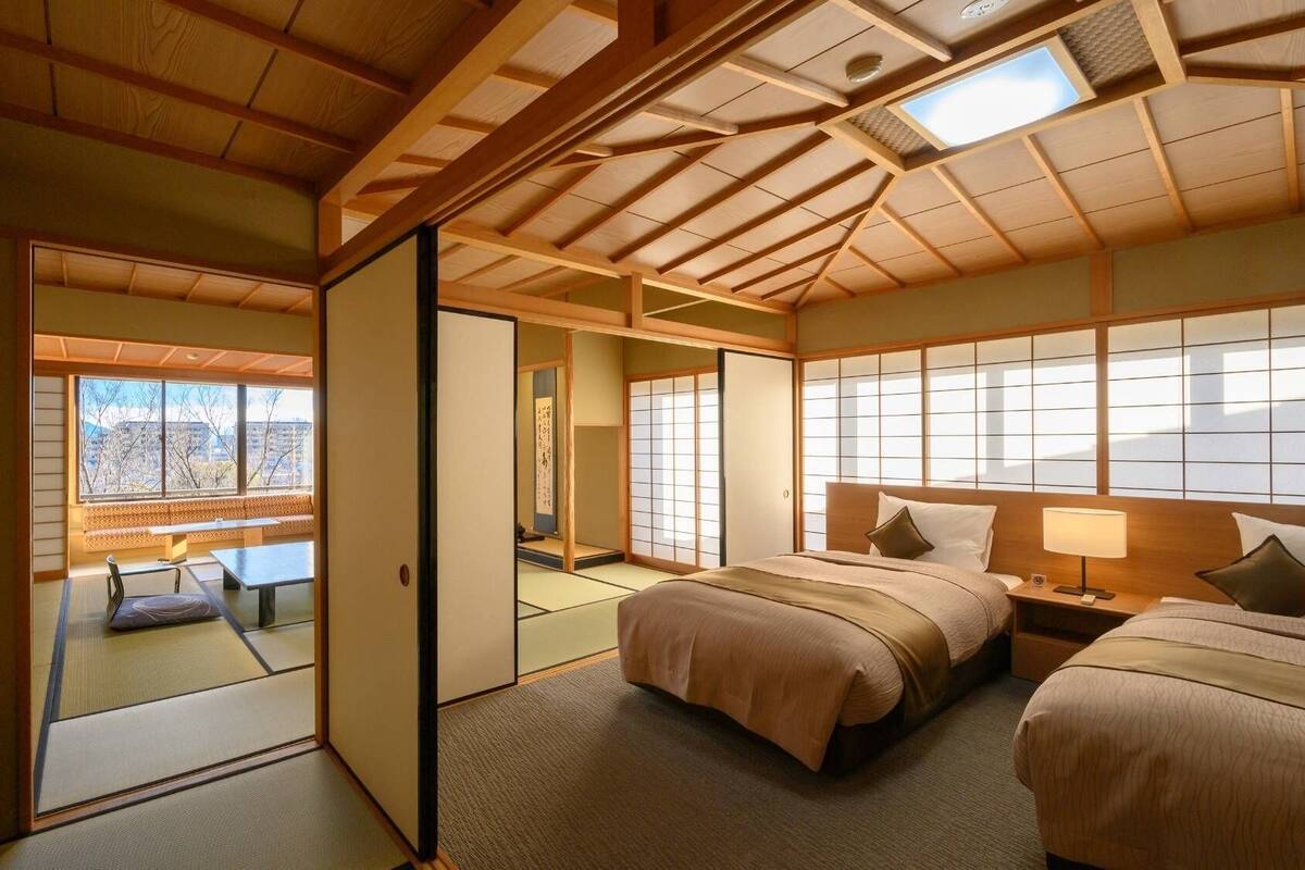 A traditional Japanese-style room with tatami flooring, a low ceiling with wooden beams, and sliding doors leading to a balcony.