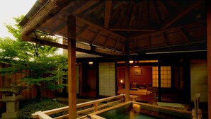 A traditional Japanese onsen with wooden benches and a stone pathway leading to the hot spring. - Tokiwa Hotel (Kofu)