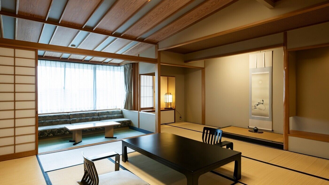 A traditional Japanese room with tatami flooring, a low table, a sofa, and sliding doors.