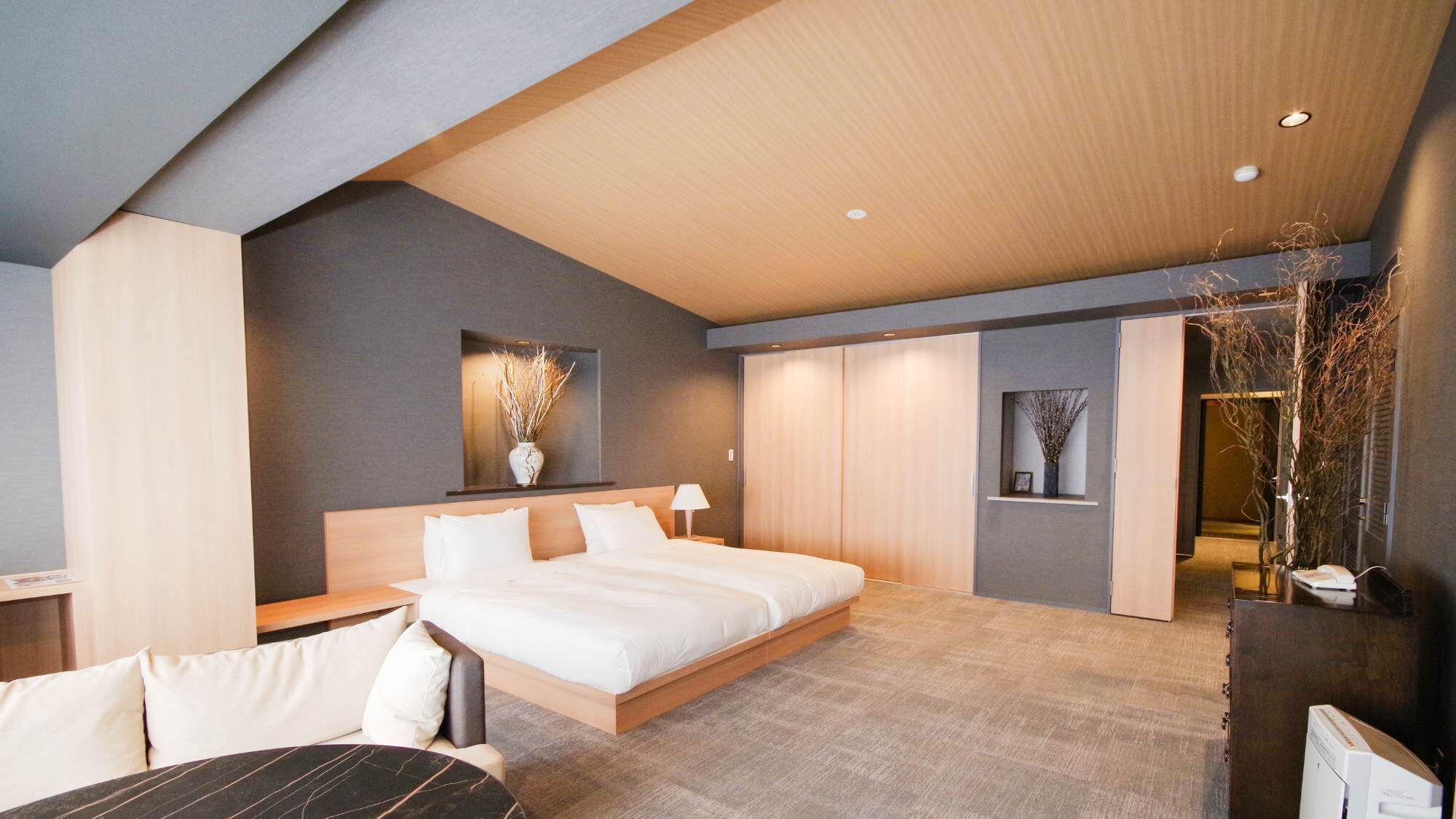 A modern hotel room with a large bed, a desk, and a seating area.