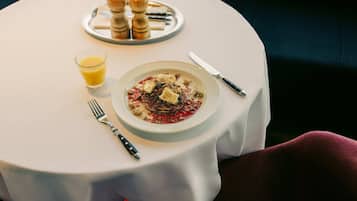 A dining table with a plate of food, a glass of orange juice, and cutlery.
