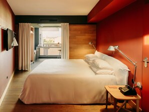A hotel room with a bed, a desk with a telephone, a lamp, and a view of the outside. - Casa Camper Berlin (Berlin)