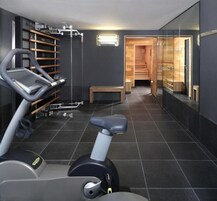 A modern gym with a stationary bike, a treadmill, and a wooden bench.
