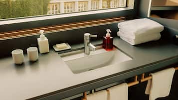 Un baño con lavamanos, dispensador de jabón y toallas.