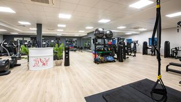 Un gimnasio con cintas de correr, máquinas de pesas y un entrenador de suspensión.