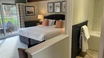 Un dormitorio con cama, mesita de noche, lámpara, ventana con vistas al exterior y zona de ducha.