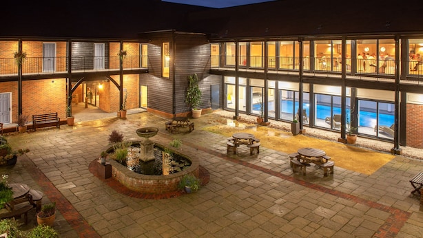 Un edificio de varios pisos con piscina, mobiliario exterior y una fuente.
